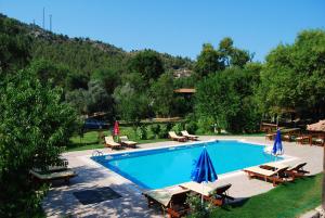 a large swimming pool with chairs and umbrellas at Doga Apartments in Kayakoy