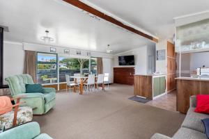 a living room with a kitchen and a dining room at Habourside - Ohope Holiday Home in Ohope Beach