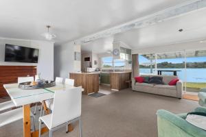a living room with a kitchen and a dining room at Habourside - Ohope Holiday Home in Ohope Beach