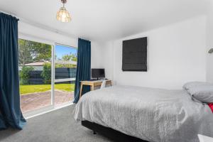 um quarto com uma cama e uma porta de vidro deslizante em Habourside - Ohope Holiday Home em Ohope Beach