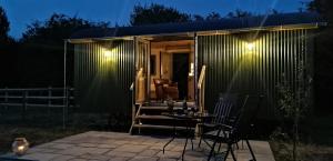 ein winziges Haus mit einer Terrasse in der Nacht in der Unterkunft The Huddle at Big Sky Brisley in Brisley