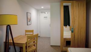 a room with a table and a bed and a mirror at Hotel Garni Fischerfleck in Ismaning near Munich in Ismaning