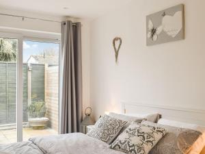 a white bedroom with a bed and a window at Lamorna in Littlehampton