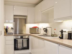 a kitchen with white cabinets and a stove top oven at Lamorna in Littlehampton