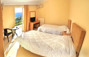 ein Hotelzimmer mit zwei Betten und einem Fernseher in der Unterkunft Dionysos Luxury Apartments in Nydri