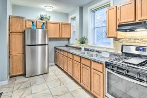 Una cocina con gabinetes de madera y un refrigerador de acero inoxidable. en Quiet Chicago Townhome Walk to Subway Stations, en Chicago
