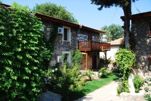a stone house with a balcony and a yard at Doga Apartments in Kayakoy