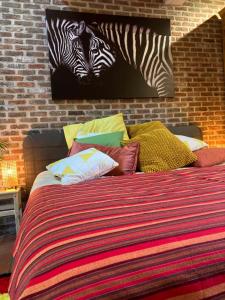 a bed with colorful pillows and zebras on the wall at Karibu Keerbergen in Keerbergen +7 photos