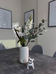 a white vase with white flowers in it on a table at Huge terrace with canal view & hotels beach access available in Dubai