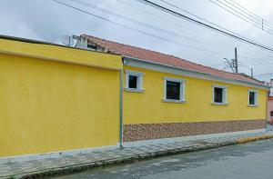 un edificio amarillo con dos ventanas en una calle en Casa a 5 minutos a pé da Basílica e da feira em Aparecida, en Aparecida