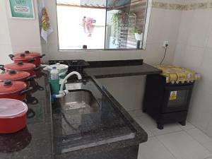a kitchen with a counter with a sink in it at Casa a 5 minutos a pé da Basílica e da feira em Aparecida in Aparecida