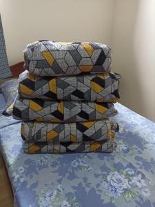 a stack of pillows sitting on top of a bed at Casa a 5 minutos a pé da Basílica e da feira em Aparecida in Aparecida