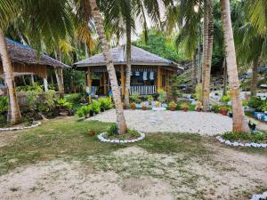 dom z palmami przed nim w obiekcie Islanders Paradise Beach w mieście Larena