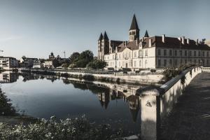 a large building next to a body of water at Hôtel Le Prieuré in Paray-le-Monial