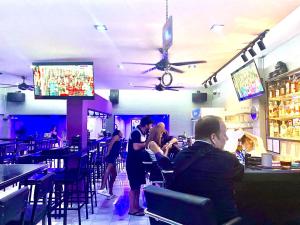 a group of people sitting at a bar in a restaurant at Barzilla Bar And Guesthouse in Pattaya