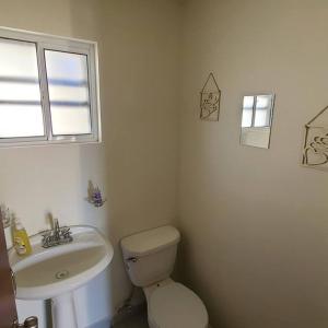 La salle de bains blanche est pourvue de toilettes et d'un lavabo. dans l'établissement Casa entera nueva, à Hidalgo del Parral
