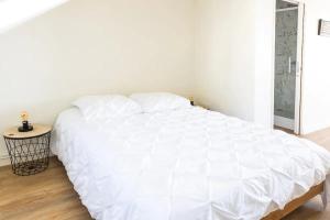 ein weißes Bett in einem weißen Schlafzimmer mit Holzboden in der Unterkunft Superbe studio 'Chardonnay' avec vue sur la vallée in Hautvillers