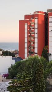 um edifício de apartamentos vermelho com o oceano ao fundo em San Clemente frente al mar con cochera em San Clemente del Tuyú