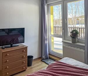 a bedroom with a television on a dresser and a window at Willa RADosna in Karpacz