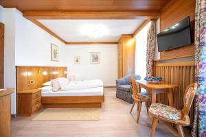 a bedroom with a bed and a desk and a tv at Garni Bondi in Selva di Val Gardena