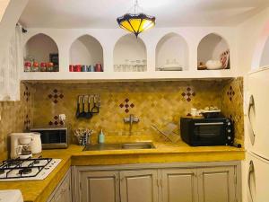 eine Küche mit Spüle und Mikrowelle in der Unterkunft Jolie petit Riyad avec piscine belle terrasse wifi in Marrakesch