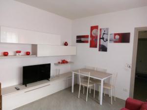 a white living room with a table and a television at Aquarius Rome Apartments in Mostacciano