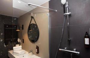 ein Bad mit einer Dusche, einem Waschbecken und einem Spiegel in der Unterkunft Apartament Biała Perła in Heudorf