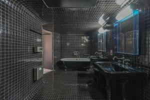 ein schwarz gefliestes Bad mit einer Badewanne und einem Waschbecken in der Unterkunft Magic suite in Saint Germain des Près (Montana5) in Paris