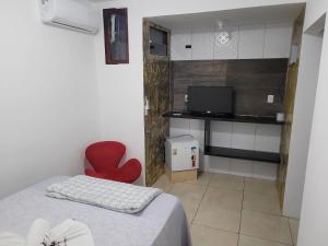 um quarto com uma cadeira vermelha e uma televisão em Hotel Veneza em Garanhuns