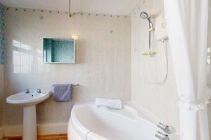 a bathroom with a white tub and a sink at Alberts Retreat in Abergele