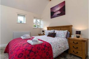 a bedroom with a red bed with towels on it at Beudy Bach in Llanrwst