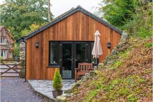 a wooden building with a bench and an umbrella at Beudy Bach in Llanrwst