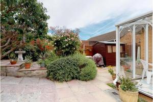 a garden with a patio and a house at Aderyn Du in Abergele