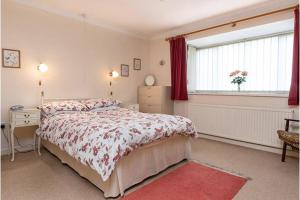 a bedroom with a bed and a desk and a window at Aderyn Du in Abergele