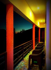 - une rangée de chaises sur un balcon la nuit dans l'établissement Pandava's Cafe & Stay, à Chopta