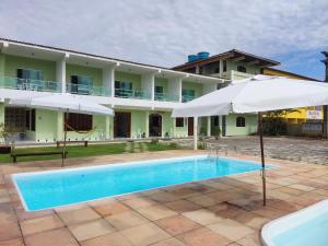 a villa with a swimming pool and an umbrella at POUSADA PRAIAMAR in Prado