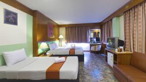 a hotel room with two beds and a television at Silom Avenue Inn in Bangkok