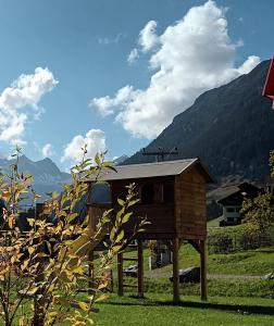 a small house in a field with mountains in the background at Ferienwohnung Kaufbeurerhausblick in Hinterhornbach