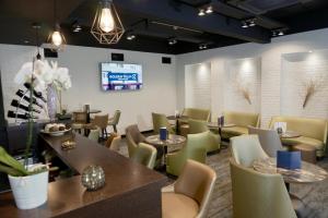 a restaurant with tables and chairs and a television at Golden Tulip Roissy Saint Witz in Saint-Witz