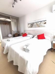 two beds in a room with white sheets and red pillows at Magical Andalusian Vacation "Los Arcos" in Tózar