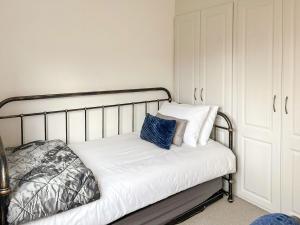 Una cama con sábanas blancas y almohadas azules. en Castlegate en Lanark