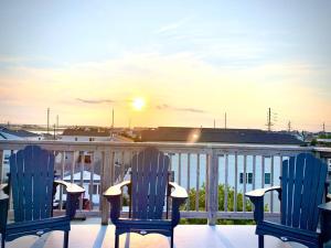 two blue chairs sitting on a balcony with the sunset at The Salt Life- Entire Home 8 Bdrm 3bath & GameRoom in Seaside Heights