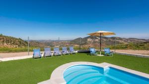 una piscina con sillas y sombrilla en Casa Rural Olvera by Ruralidays en Olvera