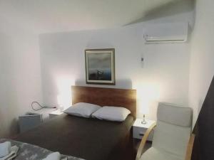 ein Schlafzimmer mit einem Bett, einem Stuhl und einem Bild in der Unterkunft Rooms Providenca in Gradac
