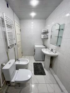 a white bathroom with a toilet and a sink at Апартаменты с тремя спальнями in Yerevan