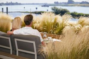 a man and woman sitting at a table overlooking the water at Traditionshaus by Zollenspieker Fährhaus in Hamburg
