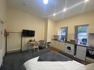 a bedroom with a bed and a kitchen with a washing machine at Modern studio apartment - great location! in Mansfield