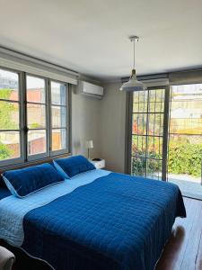 1 dormitorio con 1 cama azul grande y ventanas en Maktub Brasil - Hostal Boutique, en Santiago