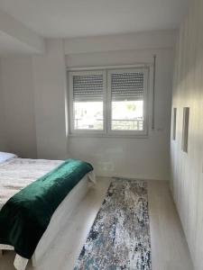 Schlafzimmer mit einem Bett, einem Fenster und einem Teppich in der Unterkunft Spacious apartment in luxury residence in Çeliku