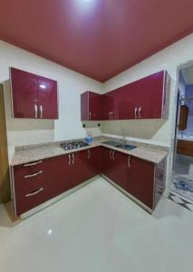 an empty kitchen with red cabinets and a sink at شقق فندقية طانطان in Tan-Tan